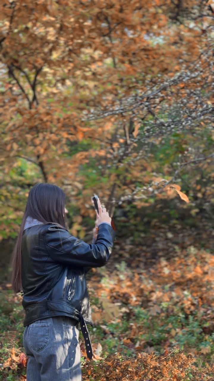 mujer tomando fotos en el parque de otoño