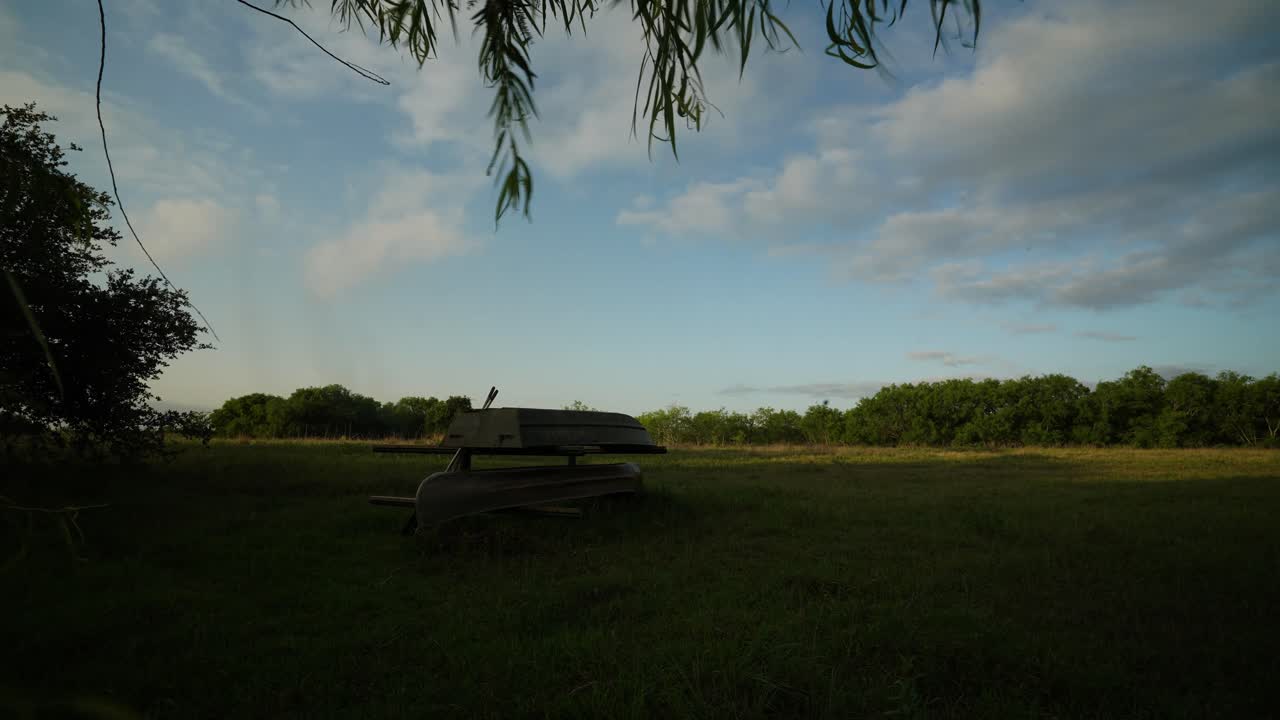 nubes de lapso de tiempo sobre pastos verdes al amanecer con almacenamiento de botes y canoas en primer plano