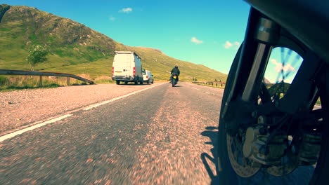 Motorcycles-on-the-open-road-through-the-mountains-and-valleys-glens-of-Glencoe-in-the-Highlands-of-Scotland-against-a-clear-blue-sky