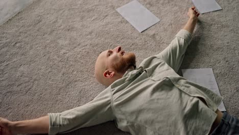 man lying on carpet with papers