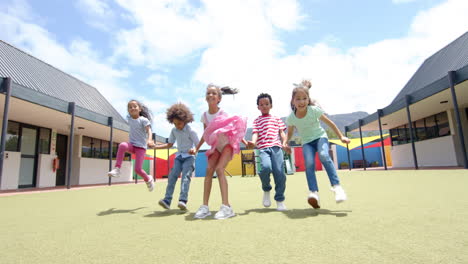 in school, group of children holding hands and jumping outdoors, smiling happily