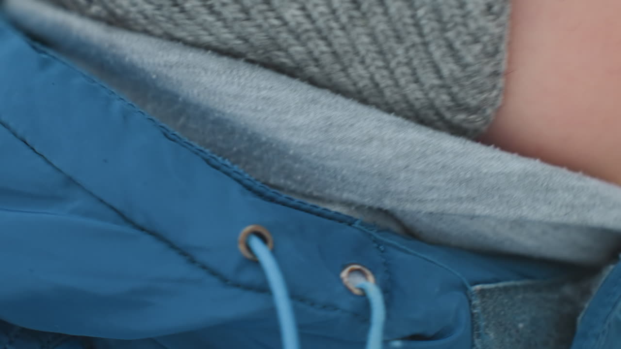 Young son blowing soap bubble outdoors, bundled in blue winter jacket with knit hat and scarf, closeup on lips and breath forming fragile bubble, soft frosty light and blurred snowy background, candid