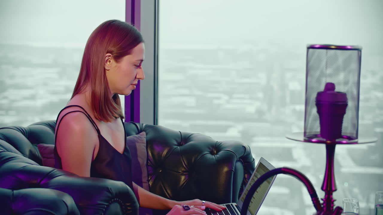 도시를 바라보는 고층 카페에서 노트북으로 일하는 여자