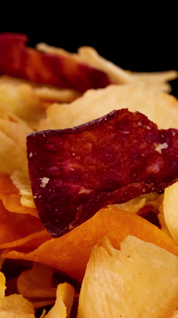 Chips Coloridos de Vegetais de Raiz Girando Sob Iluminação de Estúdio, Destacando Textura Crocante e Cores Vibrantes