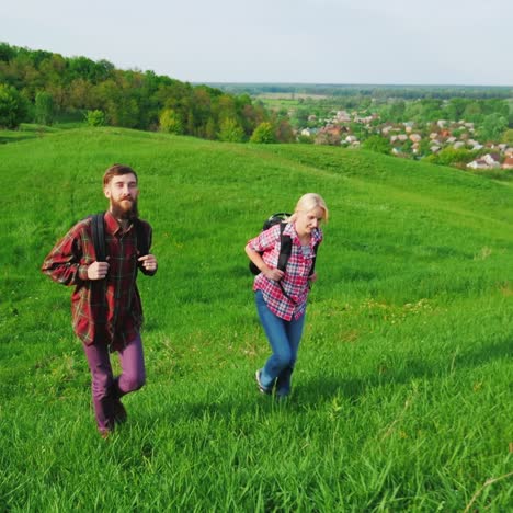 a couple of tourists with backpacks are walking along the crest of a large green hill 7