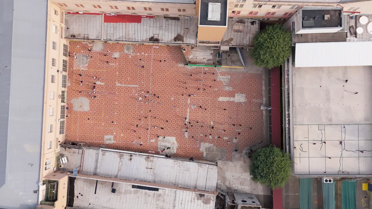 Crowd of people gathered in a large outdoor area with geometric tiled floor pattern