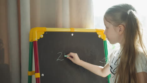 schoolgirl writes mathematical problems on blackboard