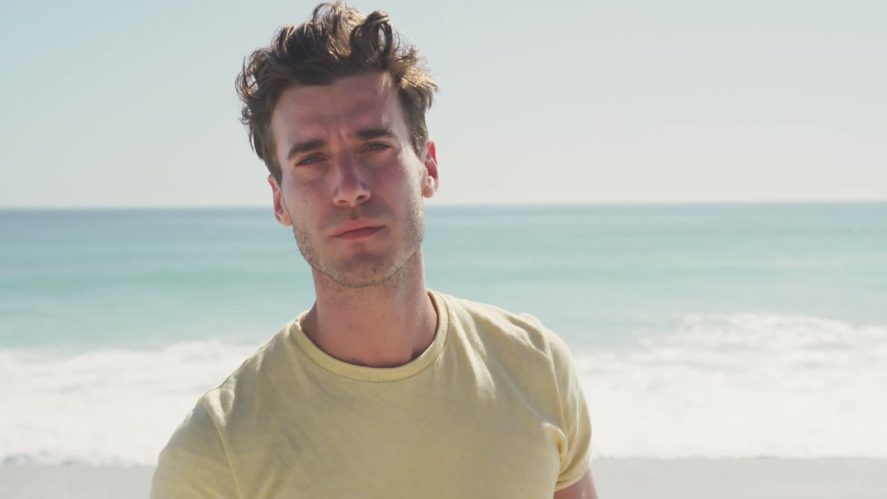 hombre caucásico mirando a la cámara en la playa