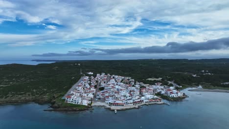 aerial parallax above es grau menorca calm spanish town under midday clouds