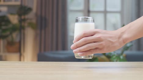 man hand place glass of fresh milk on table