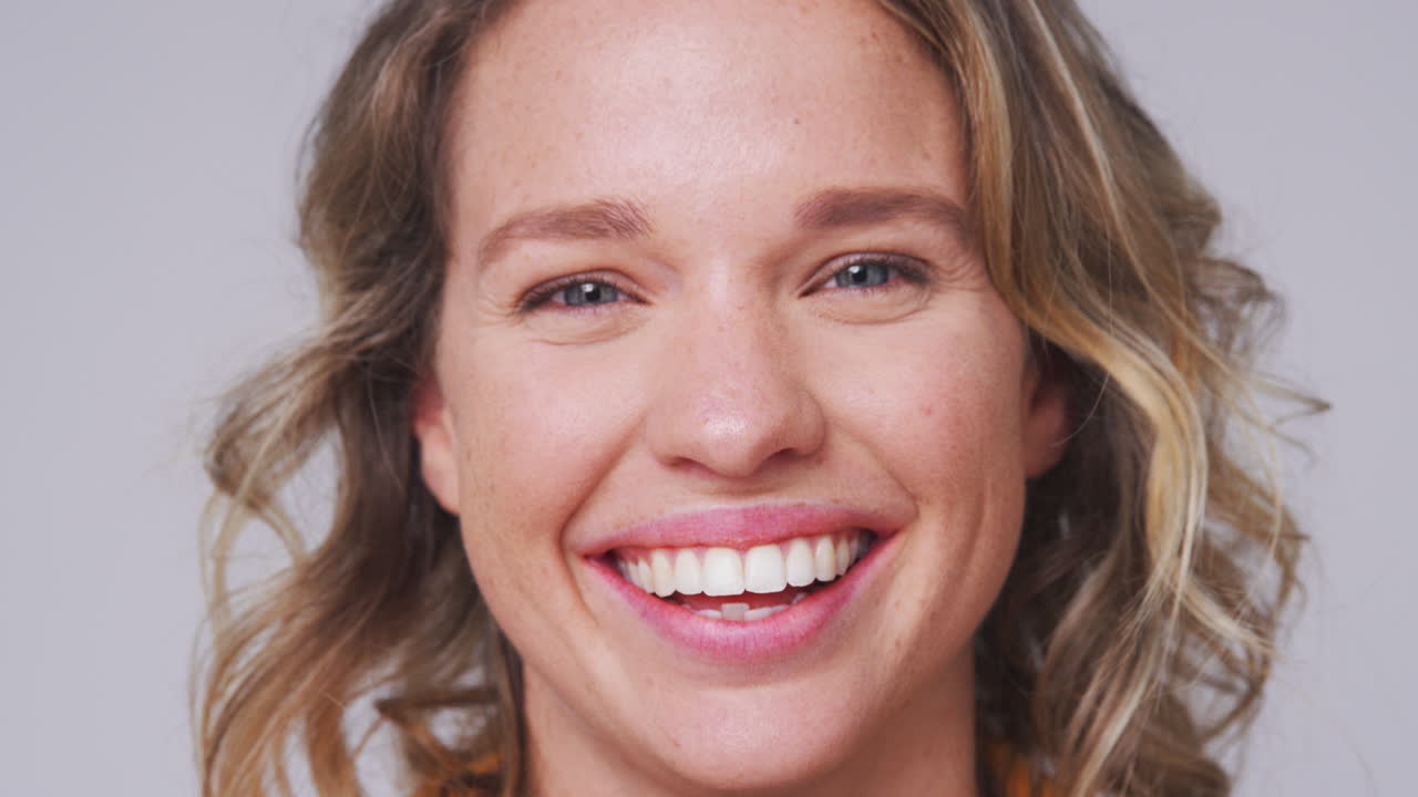 Close Up Head And Shoulders Studio Shot Of Woman Laughing At Camera In Slow Motion