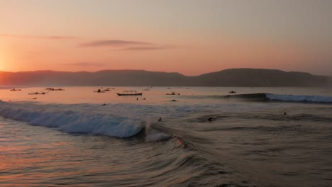 Sunrise-at-the-surf-spots-of-Gerupuk-in-Lombok,-with-a-view-on-the-bay-with-the-fishing-boats-and-surfers