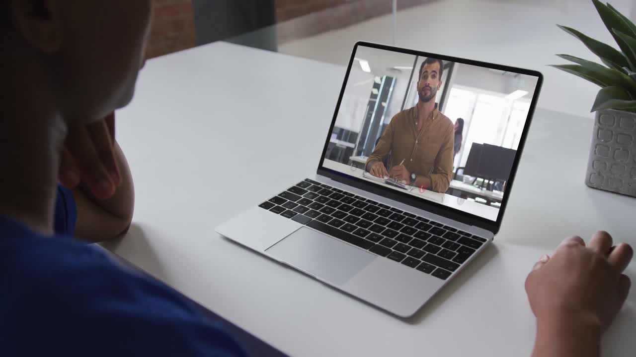 Mid section of african american woman having a video call on laptop with male colleague at office