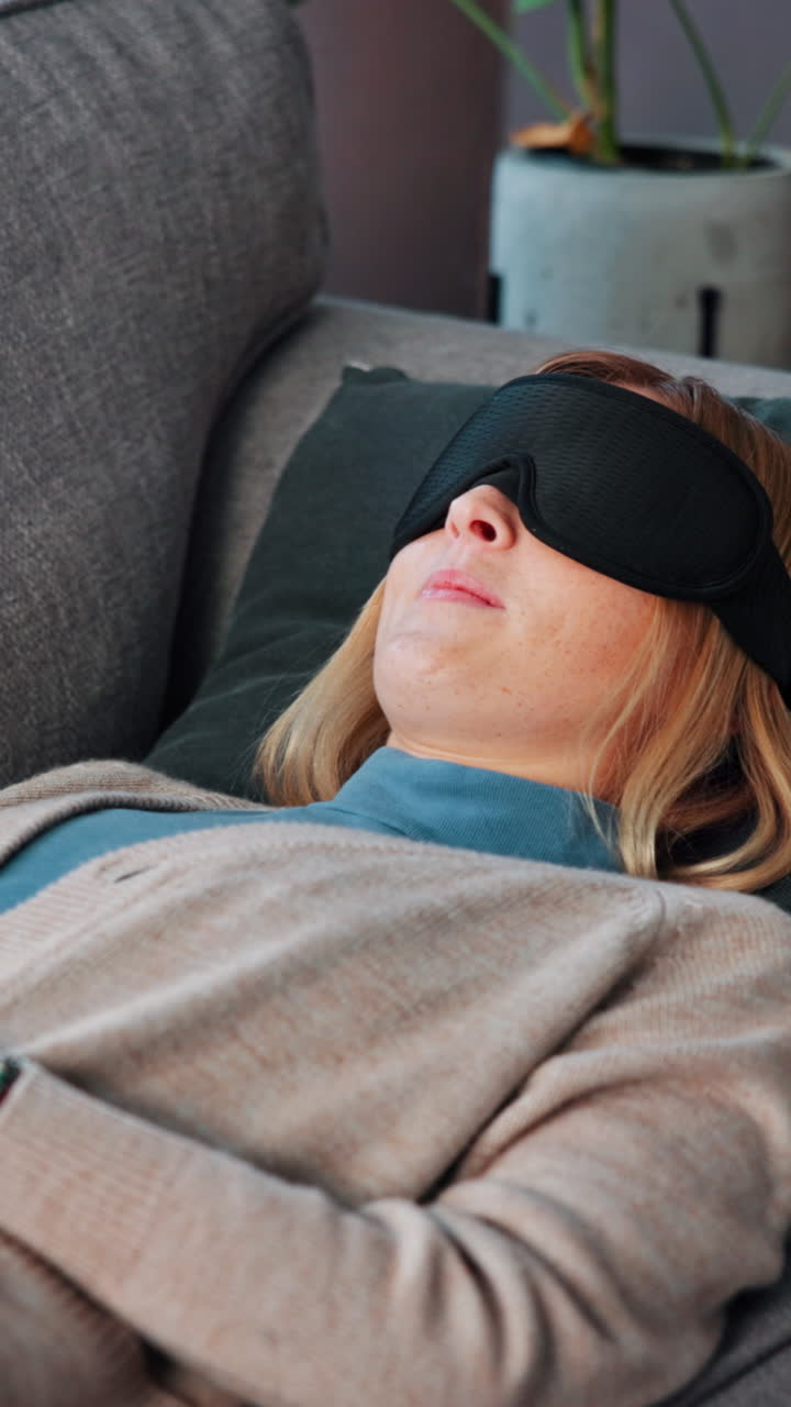 Kvinde sover på sofaen med sovemaske