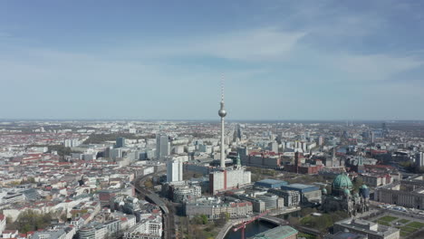 AERIAL:-Super-Close-Up-View-Circle-around-the-Alexanderplatz-TV-Tower-in-Berlin,-Germany-on-hot-summer-day