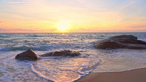 foamy sea tides rolling over stones on sandy beach at sunset in malaysia, kota kinabalu