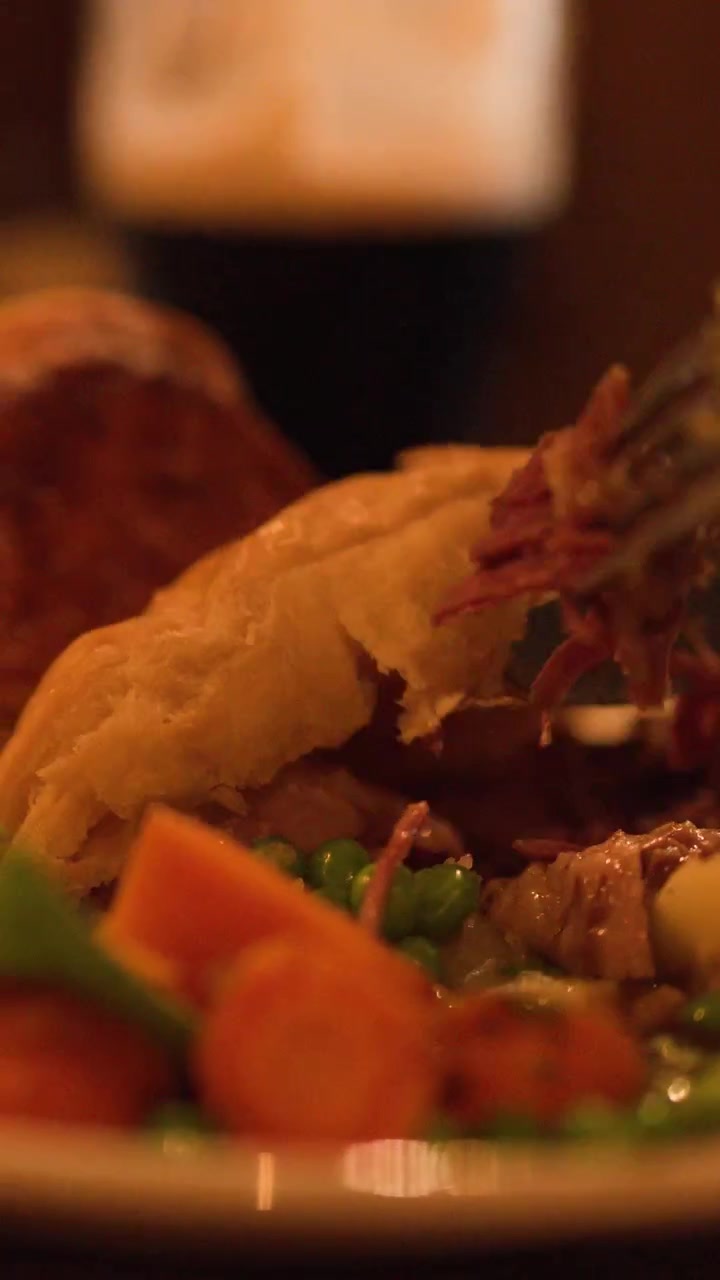 Primo piano di un tortino di carne che viene tagliato e servito, illuminazione calda, messa a fuoco ridotta, ambiente da ristorante.