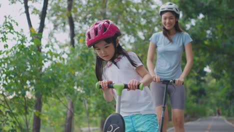 mother and daughter riding scooters in park