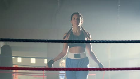 vista frontal de una joven deportista caucásica con coletas trenzadas saltando la cuerda en el ring de boxeo