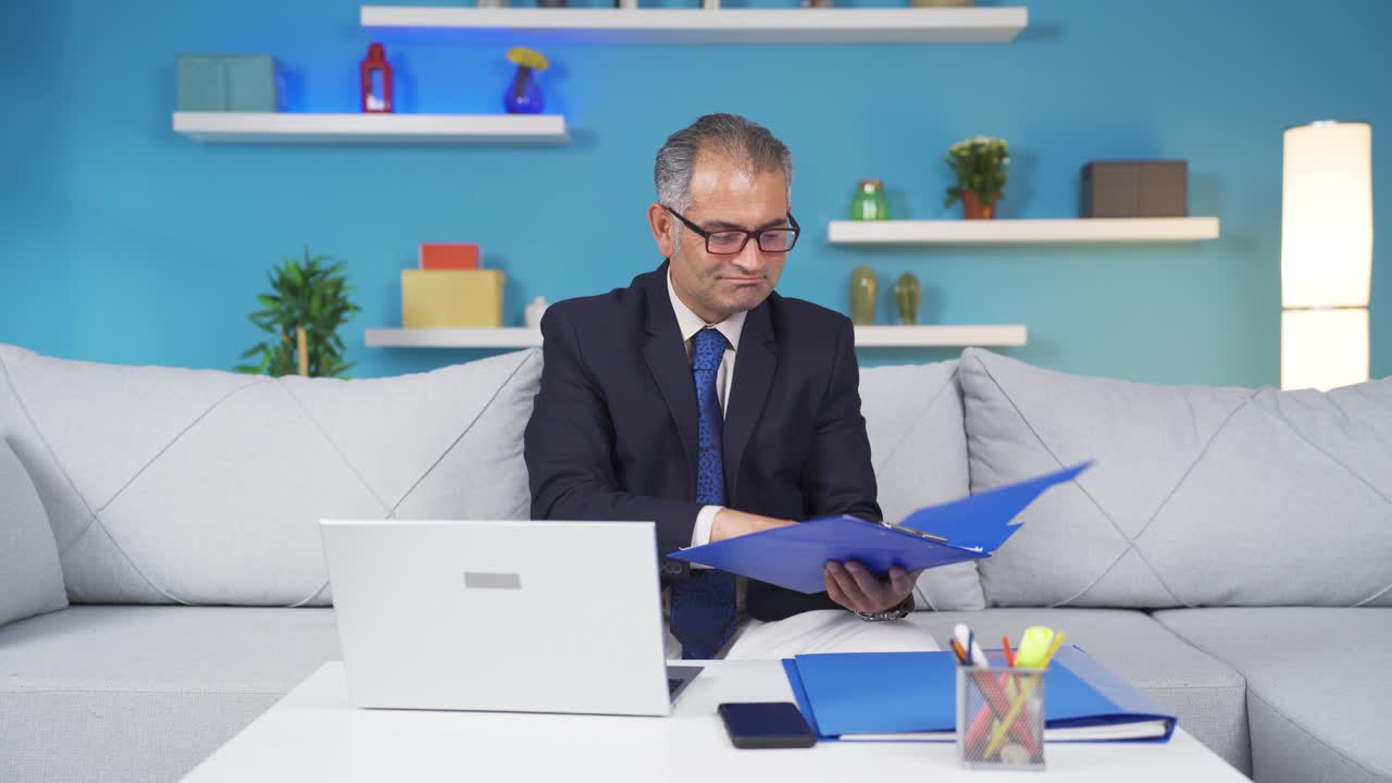 trabajador de oficina en el hogar sonriendo a la cámara mirando el papeleo.