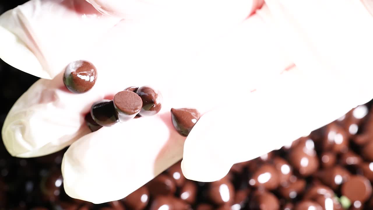 manos con guantes examinando las fichas de chocolate de cerca