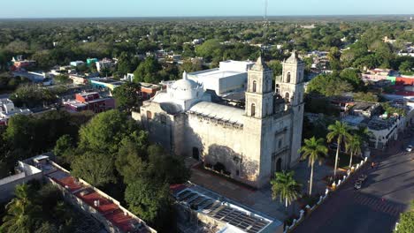 aerial trucking shot to left showing cathedral de san gervasio and the city beyond after sunrise in valladolid, yucatan, mexico