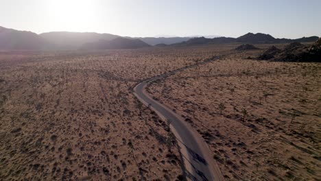 Drone-Volando-Hacia-El-Atardecer-Sobre-Una-Carretera-Vacía-En-Joshua-Tree-California