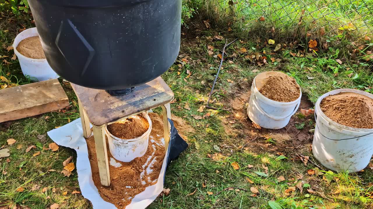 Installazione per setacciare la terra all'aperto con secchi e barili sull'erba di un giardino autunnale