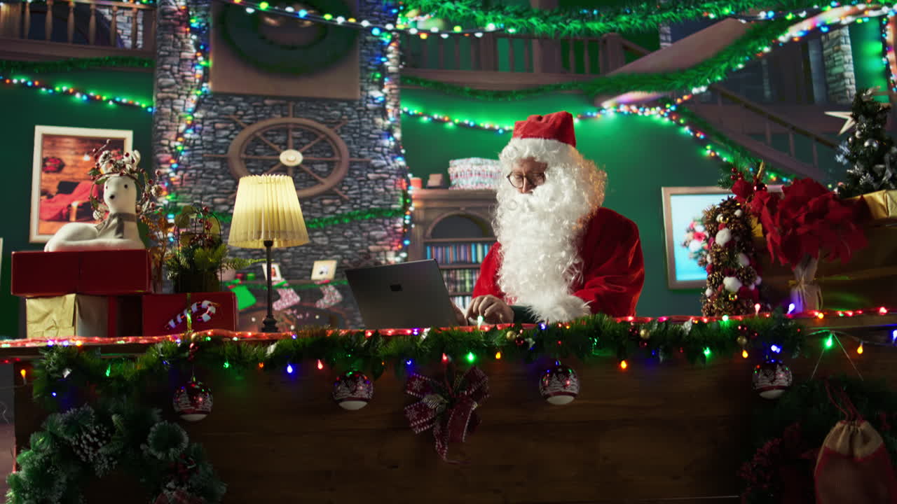 Santa Claus working on a laptop surrounded by Christmas decorations