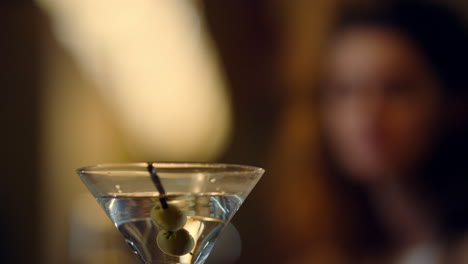 bartender putting olives in cocktail glass