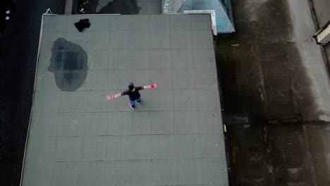 direct overhead aerial drone shot of young adult male parkour free runner doing spins on an abandoned roof top