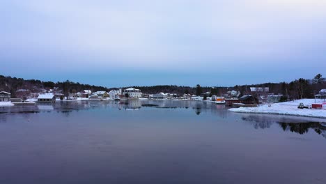 aerial footage flying low over a skim of ice on east cove of moosehead lake towards downtown greenville maine