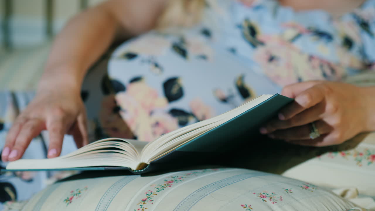 mujer embarazada lee un libro en su cama primer plano