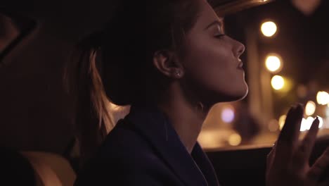 Beautiful-girl-riding-in-a-taxi-at-night-sitting-on-the-backseat-and-moving-her-head-listening-to-the-music.-Happy-woman-in-taxi