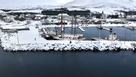 large sailboat is moored in the harbor of husavic while the harbor is covered with white snow