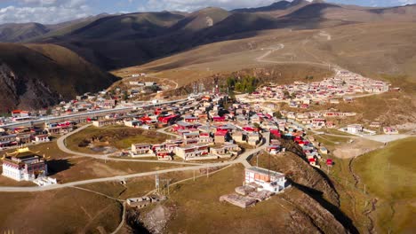 Drone-Se-Eleva-Sobre-La-Aldea-De-La-Colina-En-Los-Pastizales-Tagong-De-Sichuan,-China-Occidental