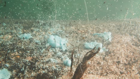 los restos caen y se derriten en el agua del lago con fondo de guijarros