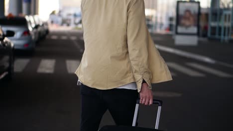 Close-Up,-Cropped-Shot-Of-Married-Man-With-The-Black-Baggage-Walking-To-The-Outside-Airport-Terminal-By-Road