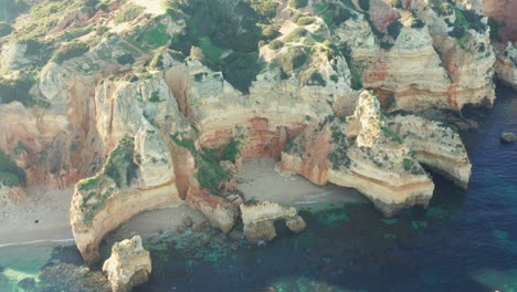 aerial paralax shot of a secluded white sand beach surrounded by limestone cliffs in the algarve region of portugal outside of lagos