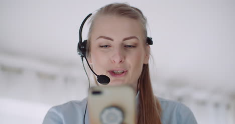 sales representative in headset speaking to client and making video conference call on smartphone