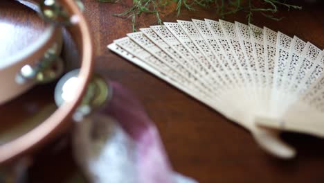 Pan-of-tambourine-and-wooden-hand-fan,-close-up