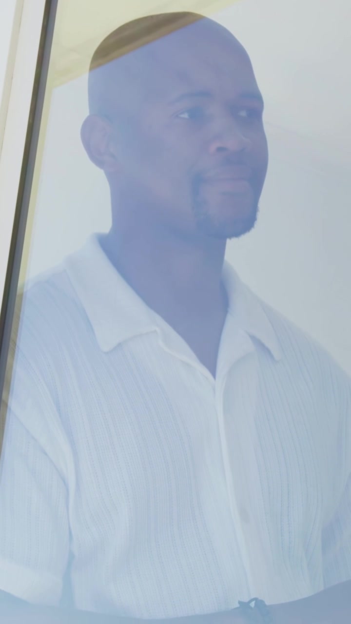 Vertical video: Shifting gaze, man turning right, blinking then smiling by door, in shirt and watch