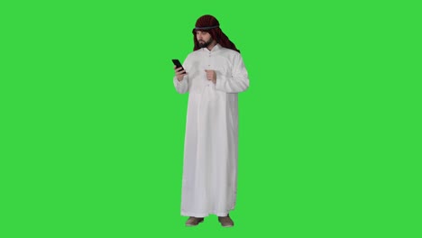 arab man using his smartphone surfing on the internet or messaging on a green screen, chroma key