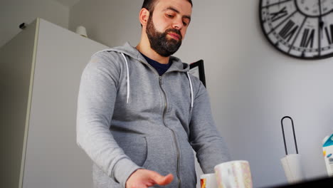 hombre barbudo guardando los platos y las tazas después de lavar