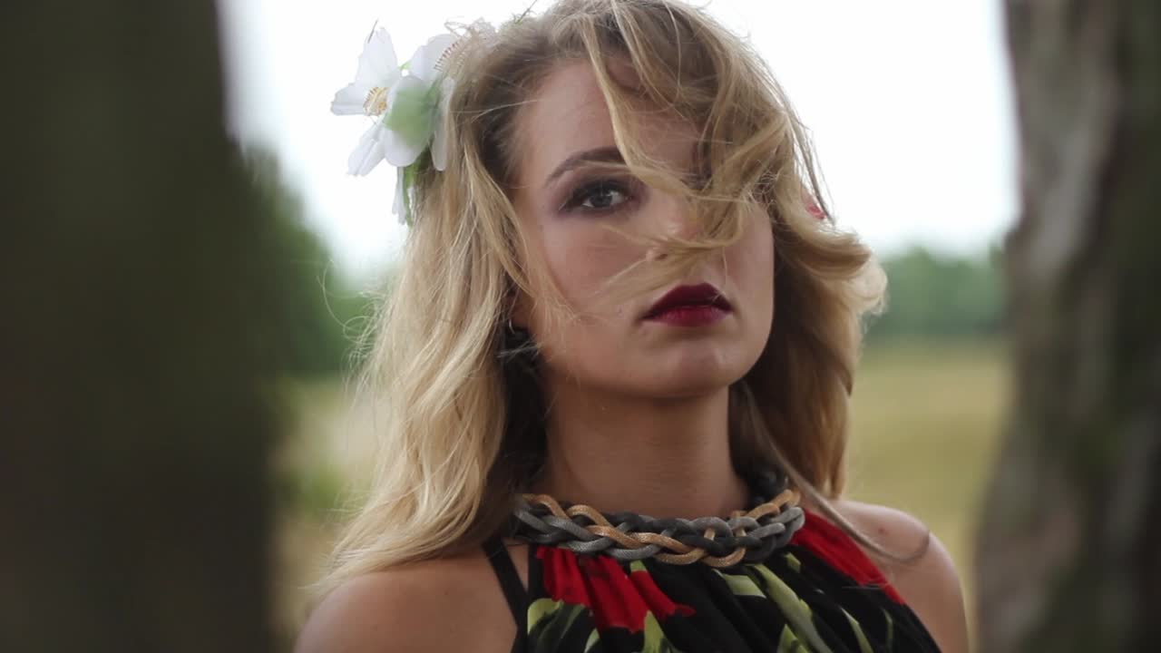 나무 뒤에 서있는 동안 카메라를보고 매력적인 젊은 여자