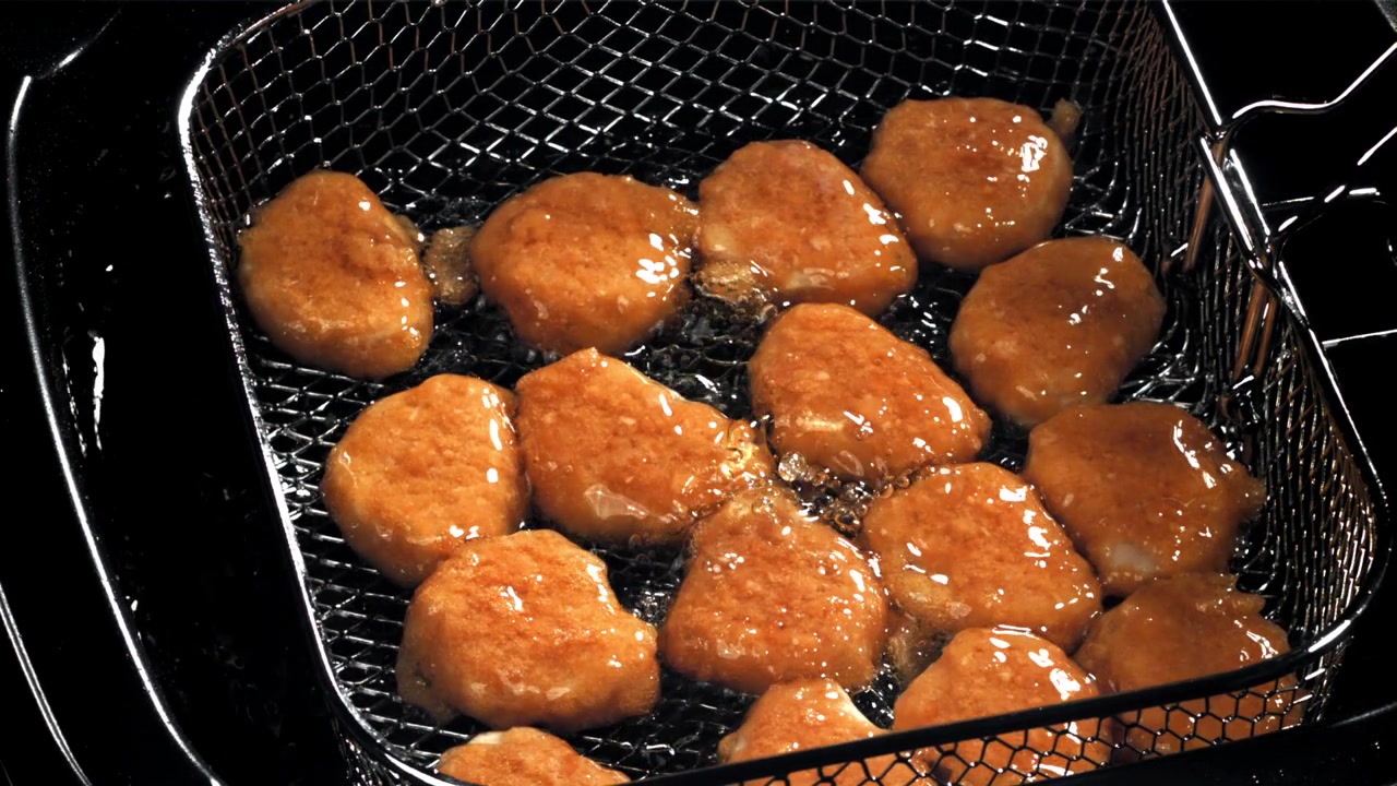 熱い油の中で揚げられているきつね色のチキンナゲット。