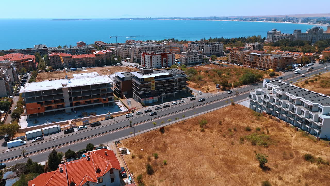 Varna, Bulgaria, 29 June 2025: Wide coastal scene showing construction and highway. The panorama captures the unfinished residential blocks, traffic, and the vast Black Sea in the distance