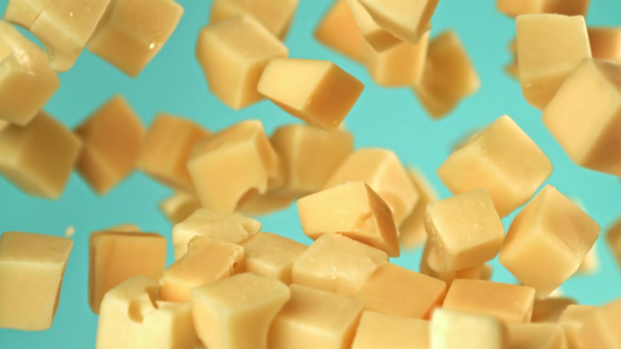 Dés de fromage tombant au ralenti sur un fond bleu