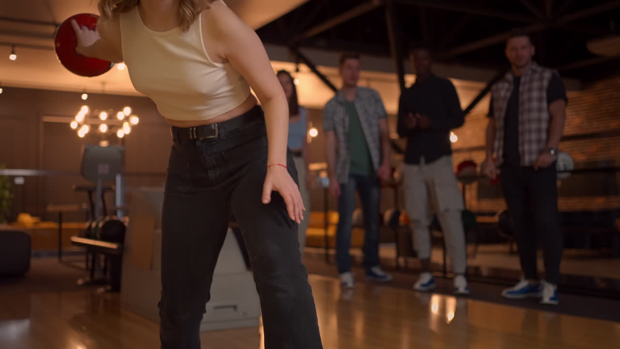 Portrait of a young woman throwing a bowling ball and knocking out a shooter who jumps and dances with joy in slow motion