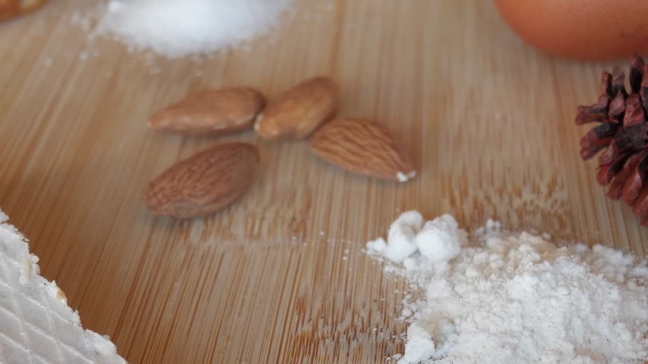 Macro close-up of almonds, sugar, and flour with marzipan piece on wooden board under soft daylight